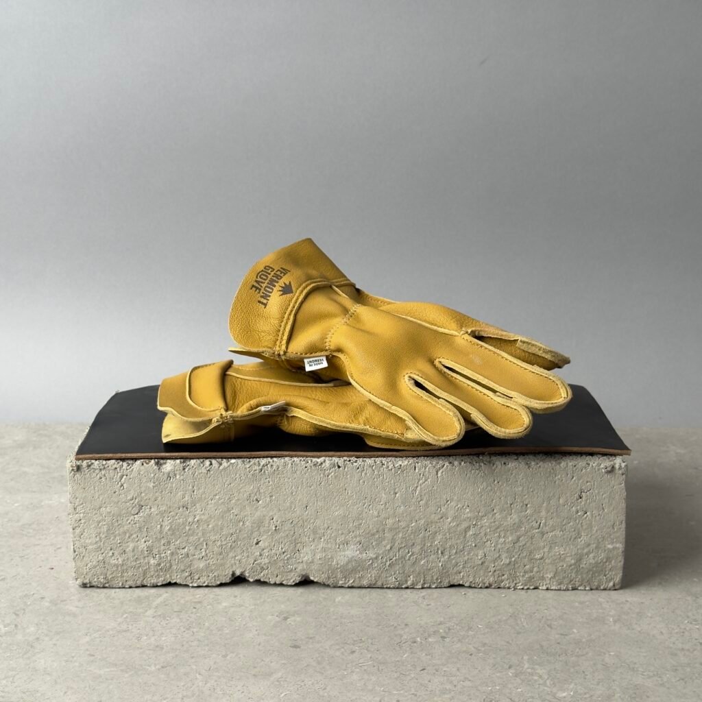 Vermont Glove The Vermonter leather work gloves on a black surface over a concrete block background