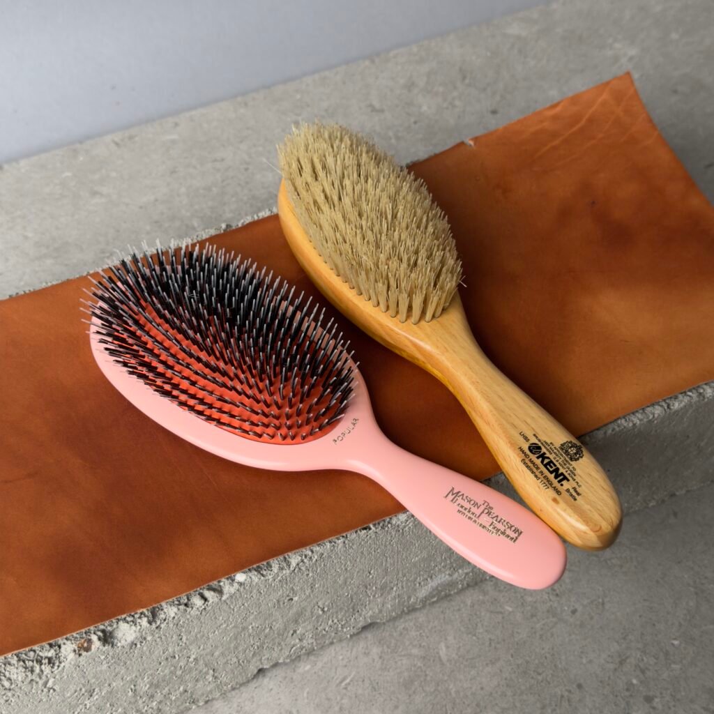 Kent LHS9 vs Mason Pearson Popular Hairbrush Kent LHS9 satinwood hairbrush and Mason Pearson Popular hairbrush side by side on leather surface